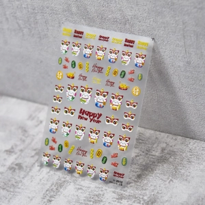 Macro detail of embossed nail stickers with lucky cat and lion dance motifs