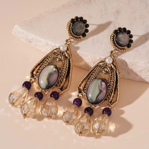 Macro view of vintage champagne teardrop crystal earrings with purple gemstones