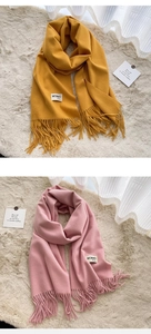 Detail of ginger and pink fringed scarves with labels on a soft fur background