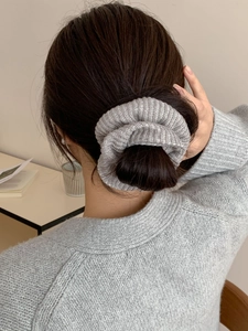 Détail d'un chouchou en maille grise montrant la texture sur un chignon de cheveux haut