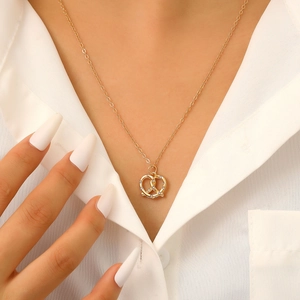 Dettaglio della collana a nodo dorata con zirconi incastonati su una camicia bianca