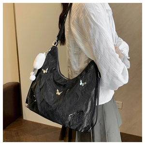 Detail of black pleated tote bag with silver butterfly charms and plush pendant