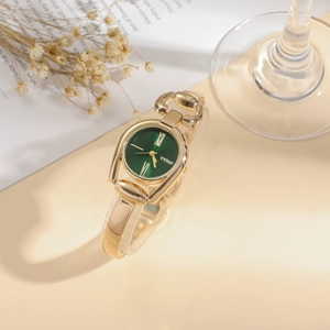 Detail shot of the gold bracelet watch with a deep green dial and Roman numerals