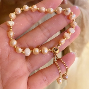 Detail of adjustable gold-plated freshwater pearl bracelet with elegant chain tassels