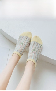 Détail de chaussette invisible en résille jaune avec vichy bleu et broderie florale