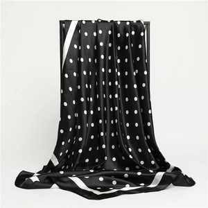 Fashionable 90cm polka dot silk scarf in black and white hanging on a minimalist stand