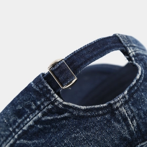 Detail van de metalen gesp en de distressed denim textuur op de achterkant van de pet