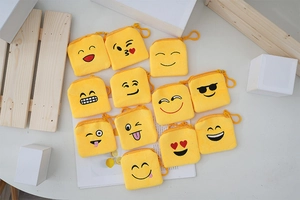 Flat lay of multiple yellow plush emoji coin purses with varied facial embroidery