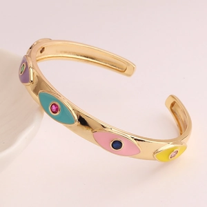 Detail of gold evil eye cuff bracelet with multi-colored enamel and small gems