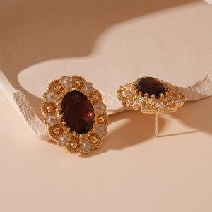 Detailed macro view of vintage gold earrings with red stones and white enamel flowers
