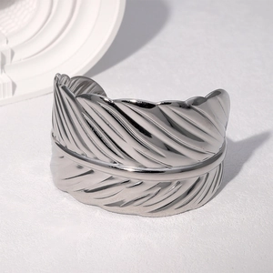 Macro shot of silver feather engraved open bangle bracelet with a polished metal finish