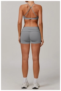 Detail of grey sports bra with cross-back straps and high-waisted seamless fitness shorts