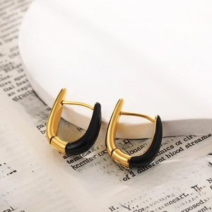 U-shaped gold hoop earrings with black enamel drip oil finish on a white podium
