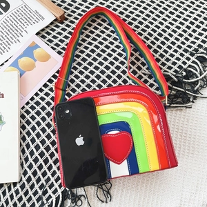 Detailed close-up of rainbow striped crossbody bag featuring a glossy red heart patch