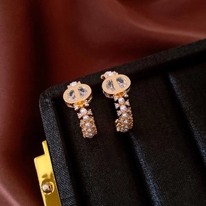 Close-up of gold-plated CD letter earrings with pave zircon and elegant faux pearls