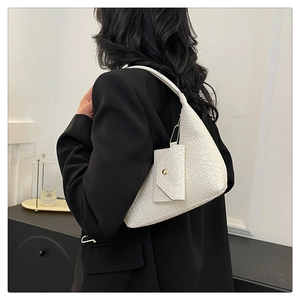Detailed side view of white woven texture shoulder bag on a model with gold metal hardware