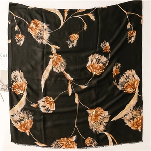 Macro detail of black and gold square scarf featuring tassel edges and floral pattern