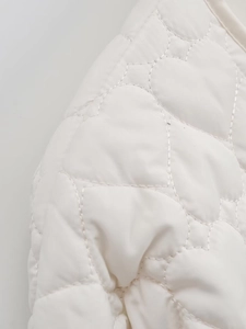 Detailed close-up of ivory white heart-shaped quilted stitching on cotton jacket fabric