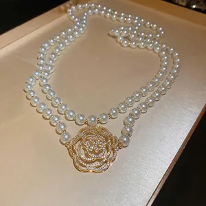Collier de perles à double rang avec un pendentif rose dorée serti de diamants brillants