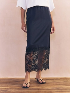 Detailed close-up of a black satin skirt featuring a delicate wide lace trim hem design