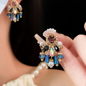 Macro shot of French vintage earrings featuring teardrop pearls and colorful crystals