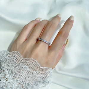 Close-up of elegant S925 silver pavé ring with zircons worn on hand over white silk