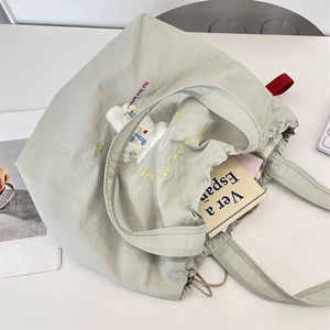 Detail view of large sage green canvas tote with embroidery and drawstring side