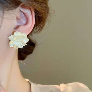 Detailed view of layered camellia petal earrings with a soft pearlescent cream finish