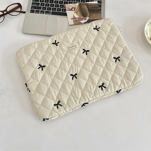 Detail of quilted tablet sleeve with bow embroidery and branded fabric tag