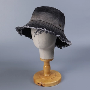 Gradient denim bucket hat with frayed edges and metal logo on a wooden stand