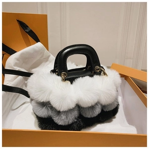 Close-up of fluffy faux fur handbag with tricolor pom-poms in luxury gift packaging