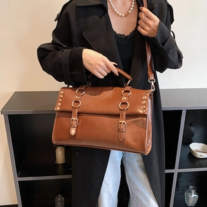 British retro brown PU leather satchel bag with buckle straps for women in a professional shot