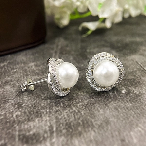 Macro shot of pearl stud earrings with zircon halo and floral wrap design detail