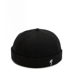 Close-up of black docker hat with white palm tree embroidery on cotton fabric