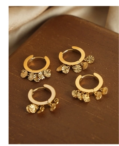 Détail de boucles d'oreilles en U dorées avec pendentifs rayés sur support en bois