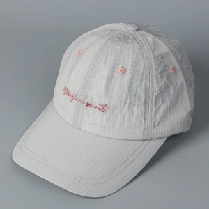 Close-up of light gray plaid fabric and pink embroidered script on baseball cap