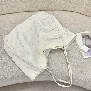 Detail of white canvas tote bag featuring silver star patterns and textured finish