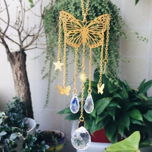 Detailed view of butterfly suncatcher with crystal prisms hanging against green plants