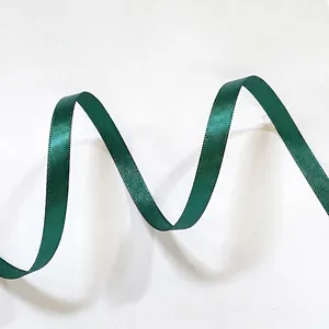 Macro shot of dark green satin ribbon with glossy finish and wavy texture for gift wrapping