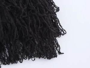 Dettaglio della trama in maglia nera e delle nappe a frangia sul set gonna moda