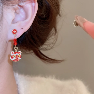 Détail de la boucle d'oreille à pompon rouge avec motif de danse du lion chinois