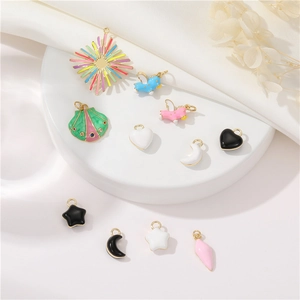 Flat lay of colorful enamel charms in star, heart, moon and shell shapes on white background