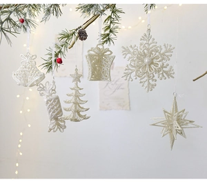 Close-up of white glitter Christmas ornaments hanging on a festive green pine tree branch