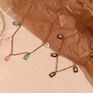 Detail of gold necklaces with colorful enamel pendants and zircon insets on textured surface