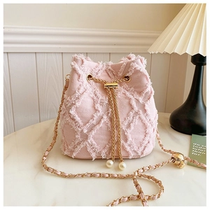 Pink canvas bucket bag detail with frayed edges, gold chain drawstring and pearl accents