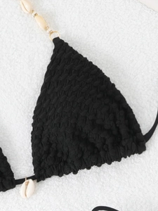 Detailed macro view of black bubble texture bikini top featuring natural shell ornaments
