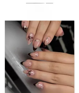 Detail of French stiletto fake nails with dark brown tips and black bow designs