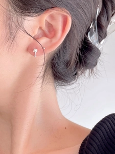 Close-up of minimalist sterling silver earring with a white pearl on a model's ear