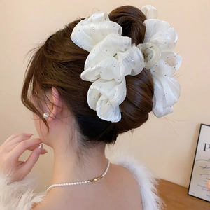 Detail of white organza bow hair claw with rhinestones styled in a refined updo