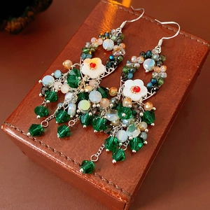 Detailansicht böhmischer Ohrringe mit grünen Kristallen und weißer Muschelblume